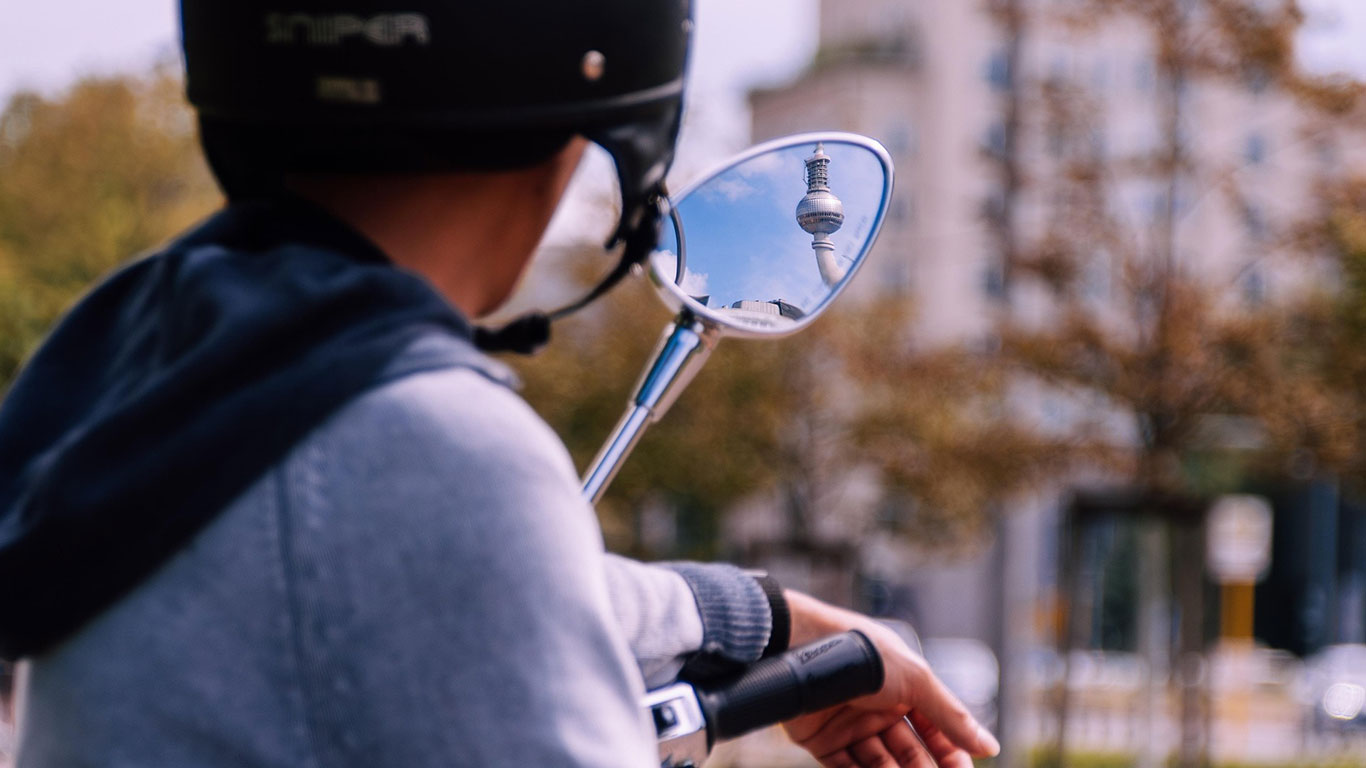 Ob für Führerschein, erste Wohnung oder als Boost - sparen für die eigenen Kinder ergibt Sinn Junger Mann mit Helm auf seinem Roller